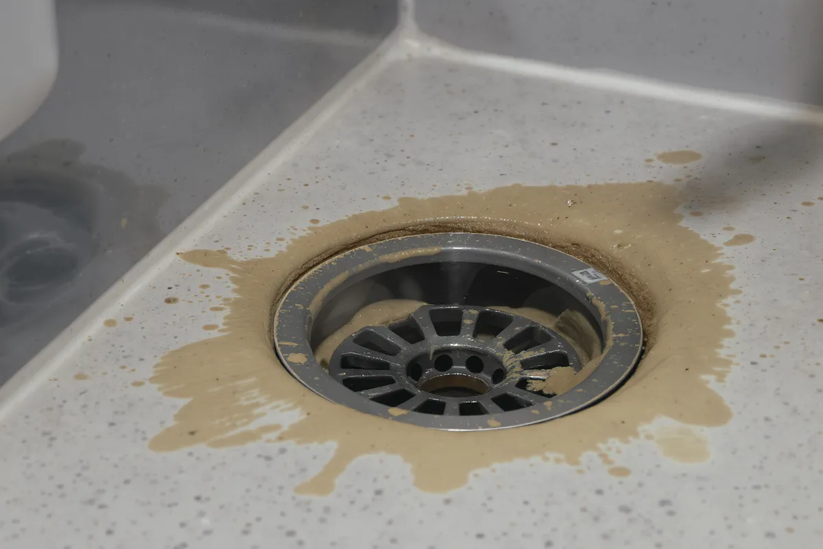 Person håller för näsan vid handfat med dålig avloppslukt hemma
